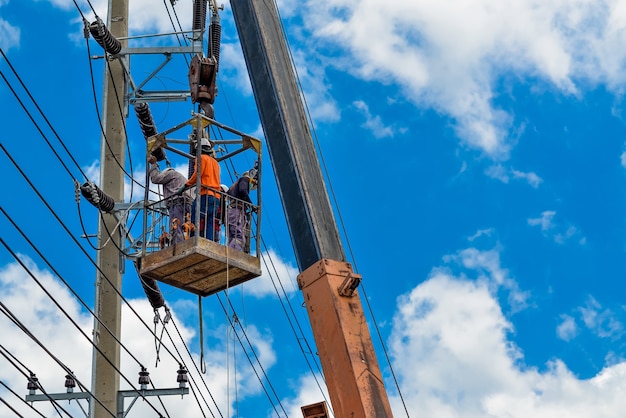 Photo electricians is in a basket on an electric pole to install and repair wires.