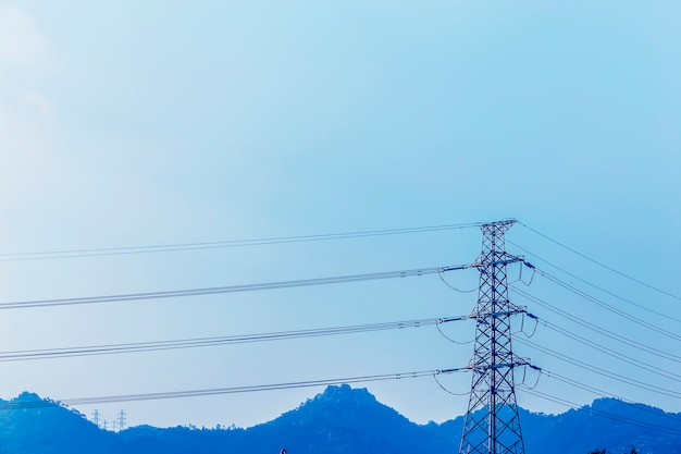 electricity transmission pylon silhouetted against blue sky at d