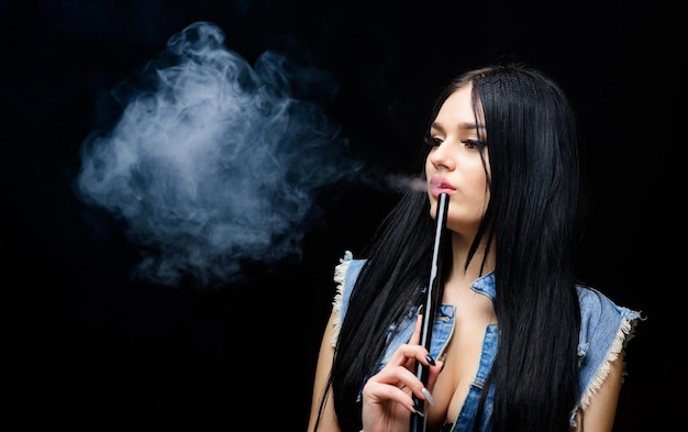 Electronic cigarette Fashion girl vaping White cloud of smoke Vaping is sexy Nicotine addiction Glamorous brunette smoking vaping device black background Girl vaping Rest and relax Hookah bar