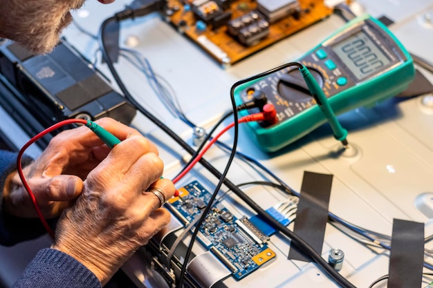 Electronic concept Hands of an elderly man with a tester measuring voltages