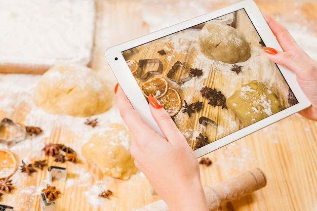 Electronic cookery book Lady using tablet to take picture of chef workplace Biscuit ingredients on screen