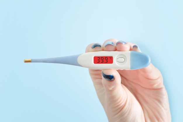 Electronic thermometer in a female hand. Elevated body temperature. Close up