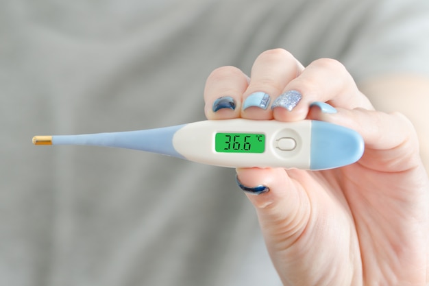 Electronic thermometer in a female hand. Normal temperature. Close up