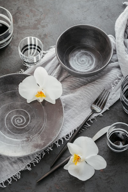 Elegance table setting with knitted grey napkin cutlery ceramic plates glasses and white orchid flowers