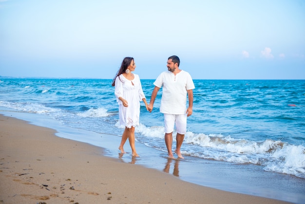  Elegant and attractive happy family man and woman walking at sea coast. Young wife and husband in love.