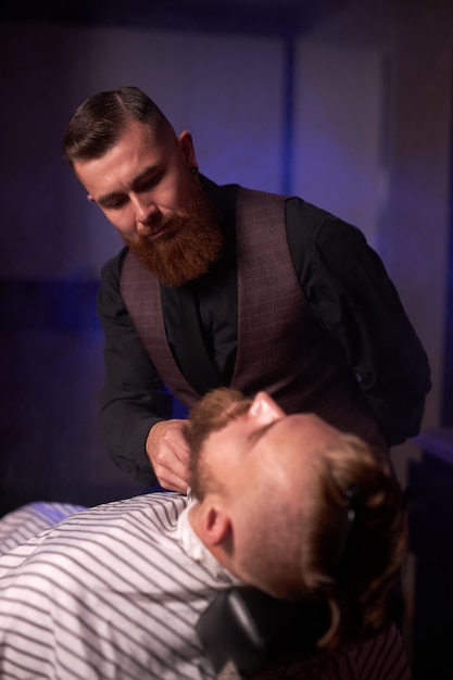 Elegant bearded businessman getting groomed at the hairdresser