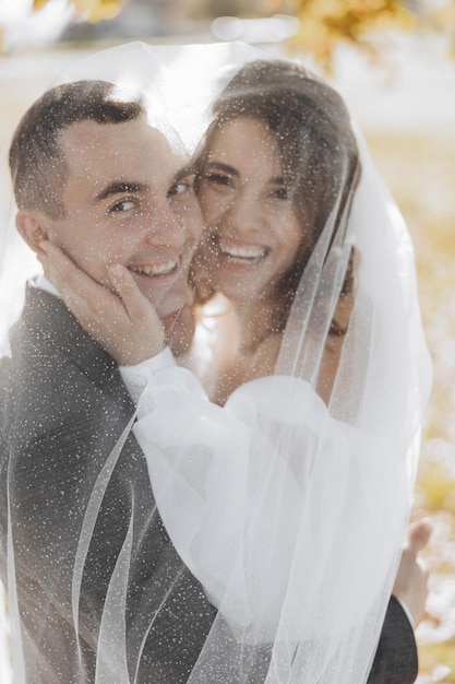 Elegant beautiful couple under veil Hugs on each other