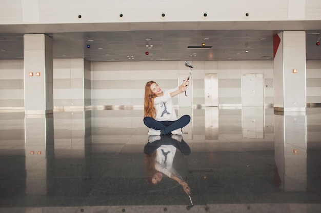 Elegant beautiful girl holding travel tickets and using a phone happy girl looking at the camera in the airport terminal Fashion woman portrait Airport terminal Business trip