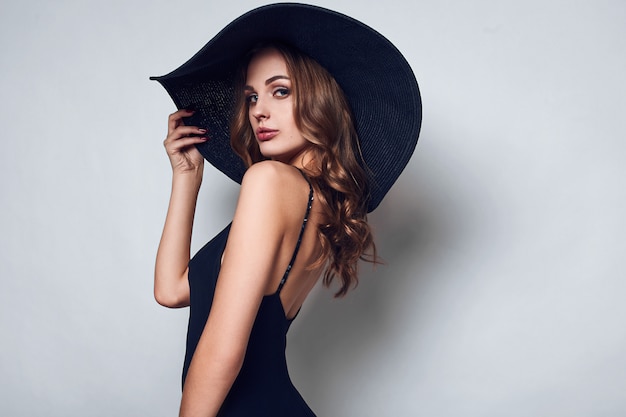 Elegant beautiful woman in a black dress and hat