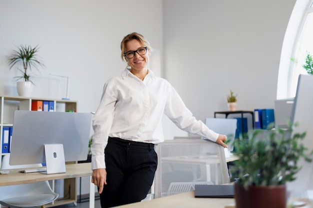 Elegant blonde businesswoman standing in your office