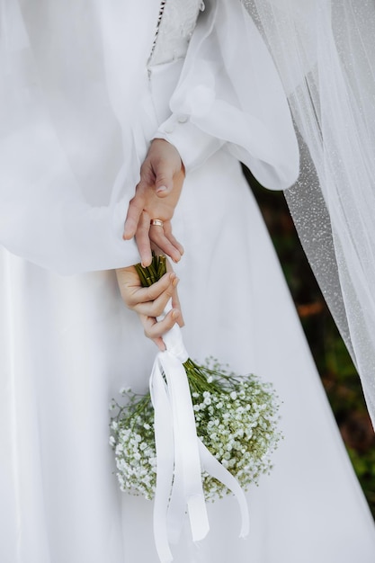 Elegant bouquet of the bride Holds behind the back Close up A bouquet of gypsophila on a white