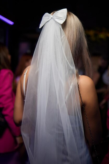 Photo an elegant bride in a beautiful veil and bow enjoying a vibrant nightclub with friends