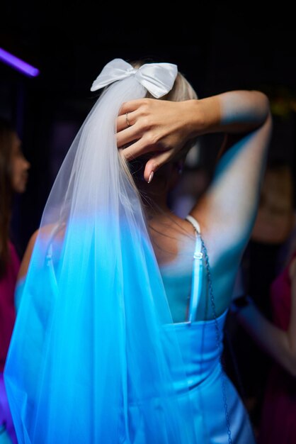 An Elegant Bride in a beautiful Veil and Bow enjoying a vibrant Nightclub with friends