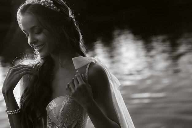 An elegant bride in a white dress enjoys nature at sunset.Model in a wedding dress in nature in the Park.Belarus. black and white photo