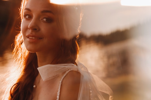 An elegant bride in a white dress enjoys nature at sunset.Model in a wedding dress in nature in the Park.Belarus