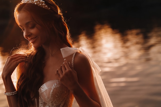 An elegant bride in a white dress enjoys nature at sunset.Model in a wedding dress in nature in the Park.Belarus