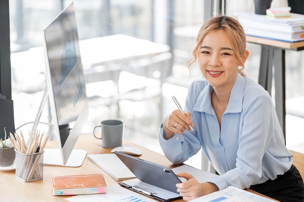 Elegant businesswoman sitting in office with digital tablet smiling to camera