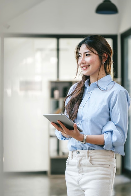 Elegant businesswoman standing in office with digital tablet