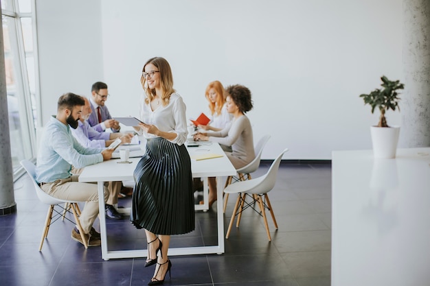 Elegant businesswoman standing in office with digital tablet