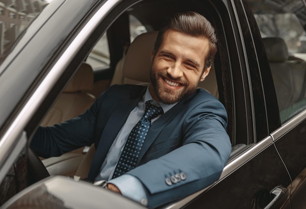 Elegant caucasian male in suit sitting at the wheel of car