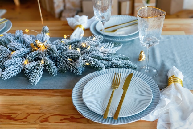 Elegant christmas table setting in gold and blue color for holiday dinner. Christmas or New Years celebration party table setting.