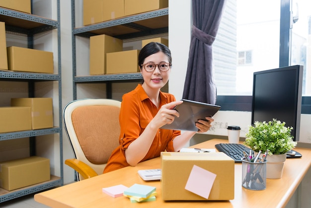 elegant confident online shopping owner woman holding mobile digital tablet computer working and looking at camera smiling.