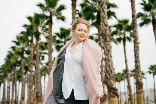 Elegant curly woman in a trendy coat enjoying the warm spring weather