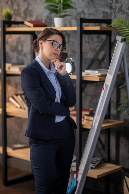 Elegant darkhaired woman standing near flipchart