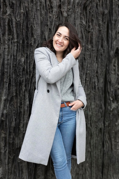 Elegant dressed young woman posing smiling isolated on dark rough wall