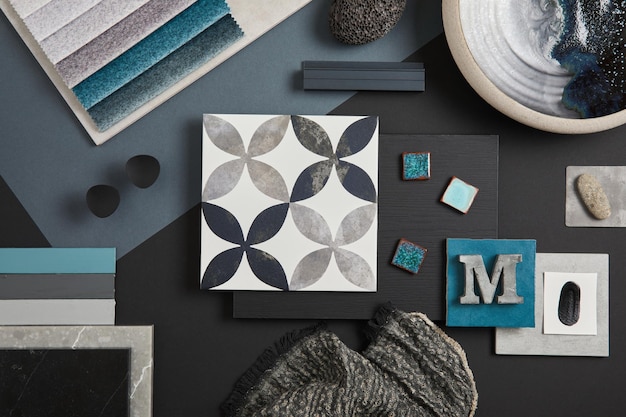 Elegant flat lay composition of interior designer moodboard with textile and paint samples panels and tiles Black blue beige and dark grey color palette Copy space Template