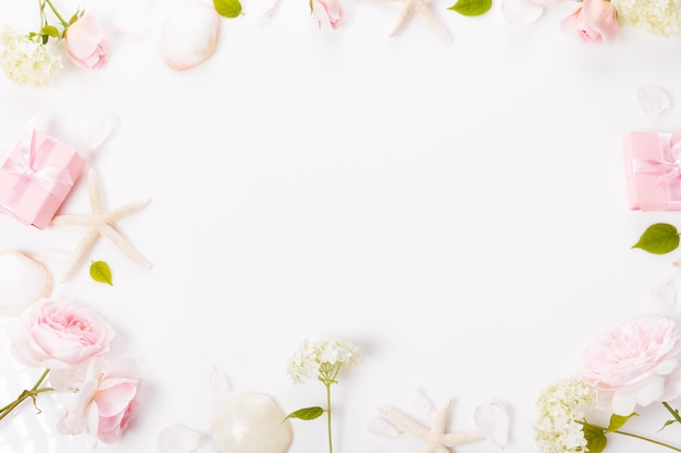 Elegant gift box and beautiful pink rose flowers on white background flat lay Space for text