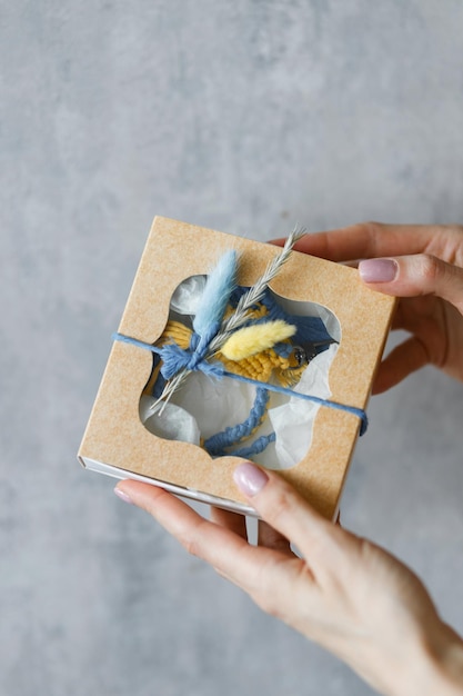 Elegant Gift Box with Decorative Feather and Blue Ribbon in Hands