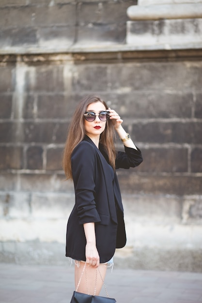 Elegant girl in sunglasses walks around the city