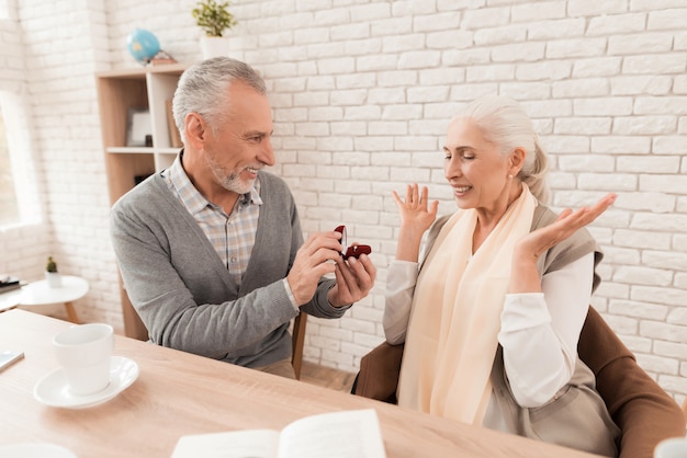 Elegant man offers one's hand to mature pretty woman.