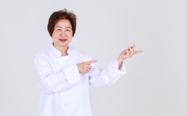 Elegant senior woman as professional chef confidently standing with arm crossed and wooden spoon and fork in restaurant kitchen. Elderly aunt expert in cooking for healthy cuisine of retired person.