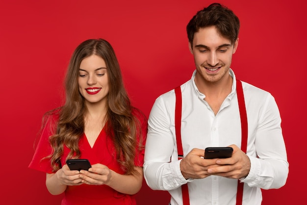 Elegant smiling couple using smartphones