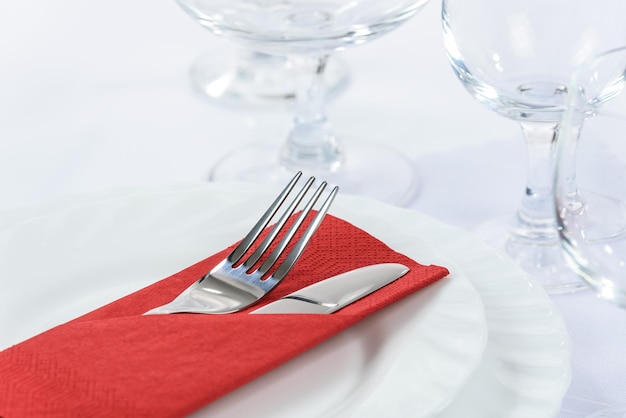 Elegant table setting in the restaurant cutlery in a red napkin on the plates and next to the wine glasses