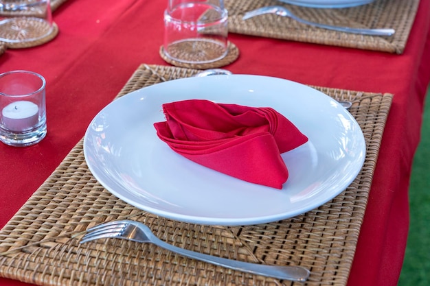 Elegant table setting with fork spoon white plate and red napkin in restaurant Nice dining table set with arranged silverware and napkins