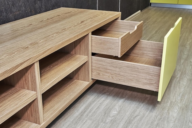 Elegant TV stand made of oak wood veneer with bright yellow facade and open drawers in minimal style