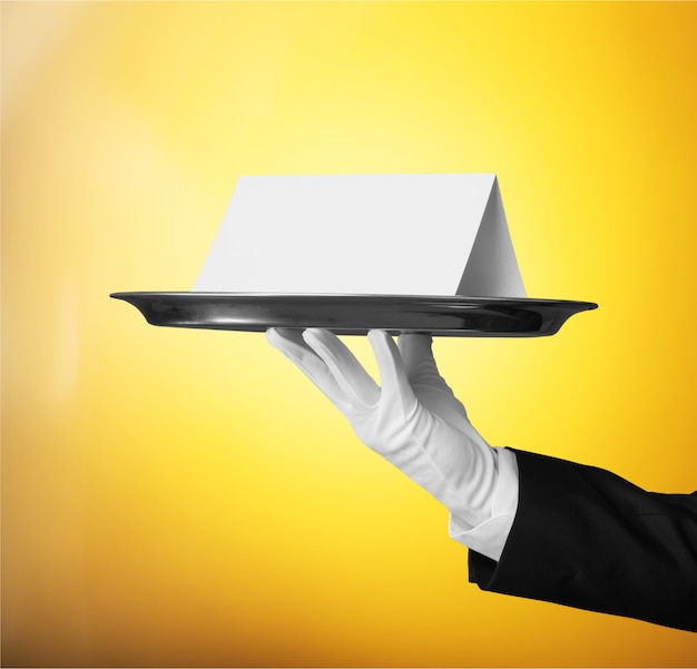 Elegant waiter hand in white glove holding  plate with note