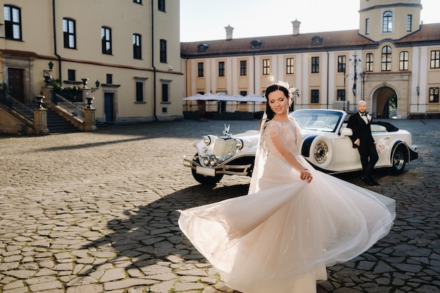 Elegant wedding couple In the courtyard of the castle near a retro car.