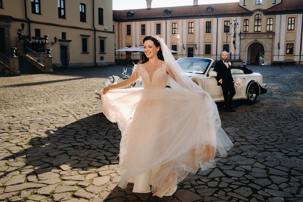 Elegant wedding couple In the courtyard of the castle near a retro car.