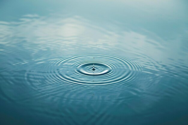 Elegant Within the center of an empty light blue canvas is a single raindrop creating ripples that