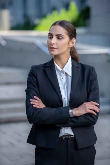 Elegant woman in a black suit standing with arms folded