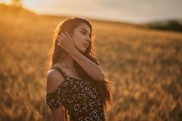 Elegant Woman In A Dress In The Wheat Field at sunset.