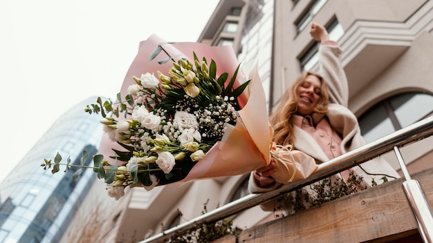 Elegant woman holding bouquet of flowers outside in the city