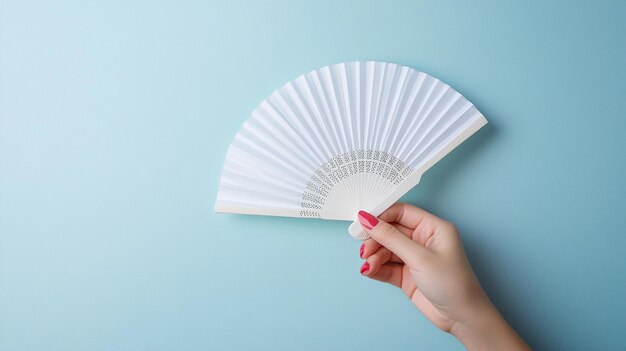 Photo elegant woman holding white hand fan on light blue background