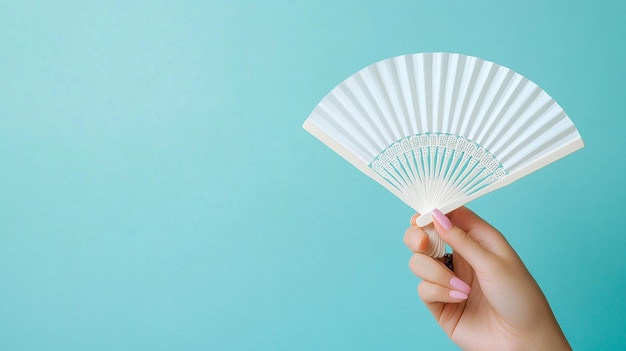 Photo elegant woman holding white hand fan on light blue background