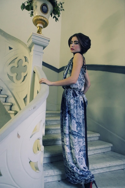 Elegant woman in long dress on vintage stairs