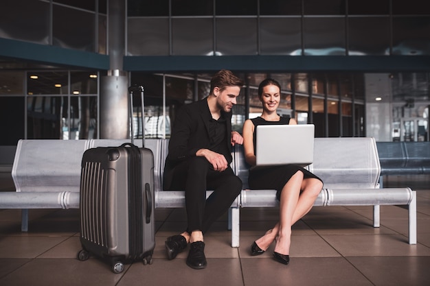 Elegant woman and man working on a laptop at the airport